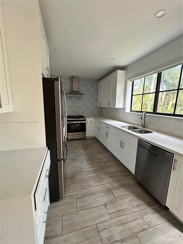 kitchen featuring white cabinetry, appliances with stainless steel finishes, sink, and wall chimney exhaust hood