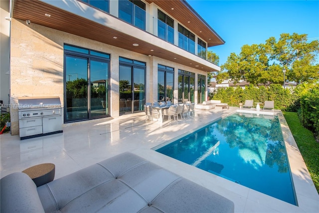 view of swimming pool featuring a patio, an outdoor kitchen, and a grill