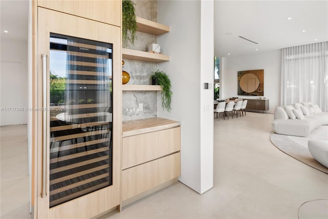 bar featuring light brown cabinets, wine cooler, and a wealth of natural light