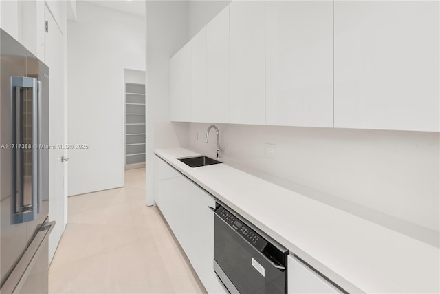 kitchen with stainless steel refrigerator, white cabinetry, sink, and dishwasher