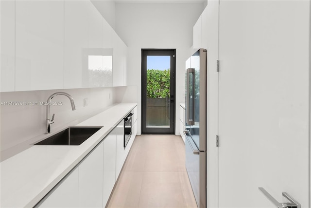 kitchen with white cabinets, sink, light tile patterned floors, appliances with stainless steel finishes, and tasteful backsplash
