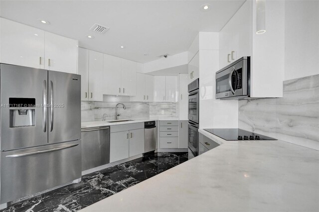 kitchen with white cabinetry, stainless steel appliances, sink, and decorative backsplash