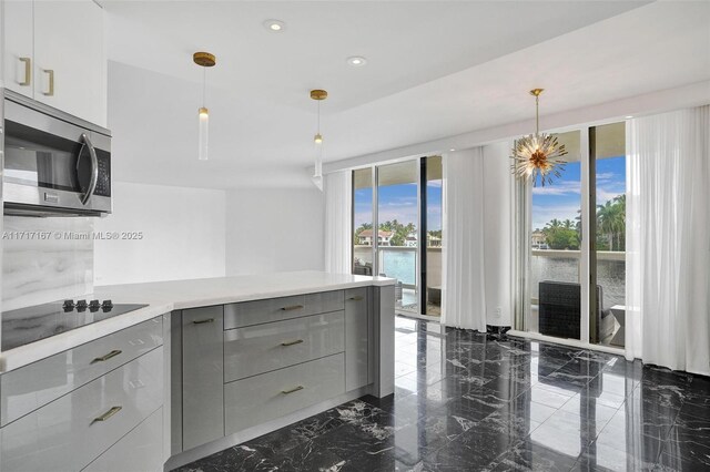 kitchen with pendant lighting, gray cabinetry, black electric cooktop, and a water view