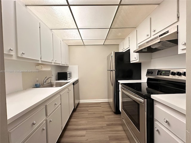 kitchen with a paneled ceiling, sink, white cabinets, and appliances with stainless steel finishes