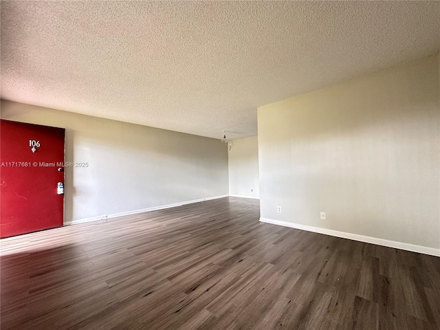empty room with baseboards, a textured ceiling, and dark wood-style flooring