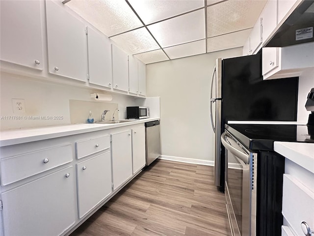 kitchen with white cabinets, a sink, light countertops, stainless steel appliances, and under cabinet range hood