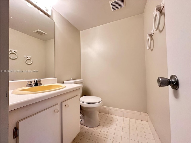 half bath with toilet, visible vents, tile patterned flooring, and vanity
