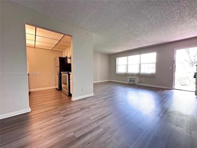 unfurnished living room featuring a textured ceiling, baseboards, a wall mounted air conditioner, and dark wood-type flooring