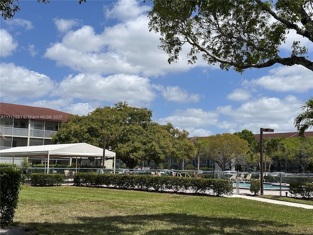 surrounding community featuring a lawn, fence, and a pool