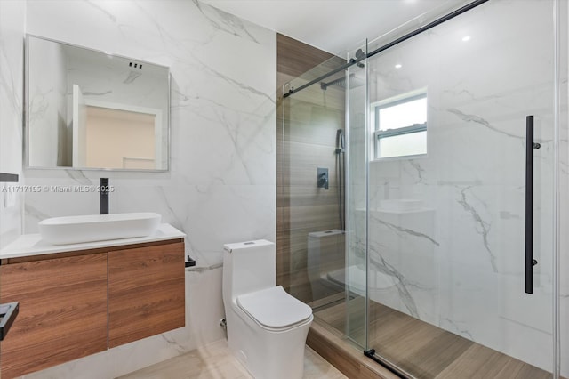 bathroom with toilet, a marble finish shower, tile walls, and vanity