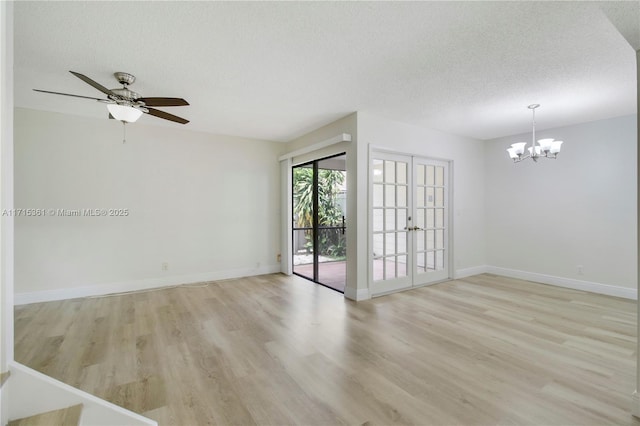 empty room with ceiling fan with notable chandelier, light wood-type flooring, a textured ceiling, and french doors