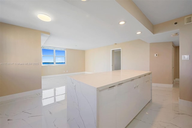 kitchen featuring light stone countertops, white cabinetry, and a kitchen island