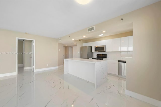 kitchen featuring white cabinets, a center island, stainless steel appliances, and tasteful backsplash