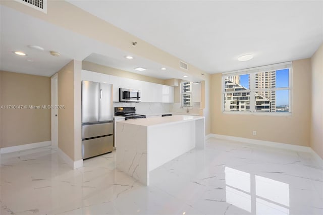 kitchen with a center island, decorative backsplash, light stone counters, white cabinetry, and stainless steel appliances