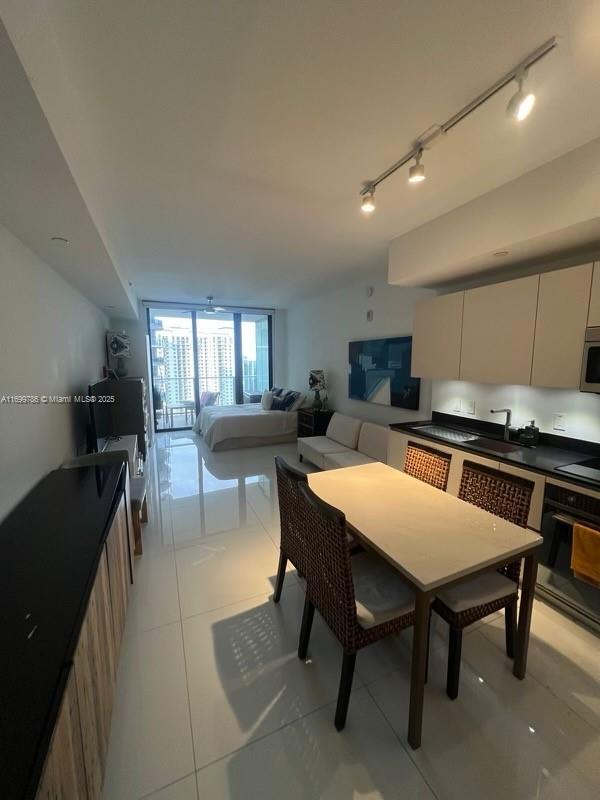 kitchen featuring floor to ceiling windows, cooktop, sink, light tile patterned floors, and oven