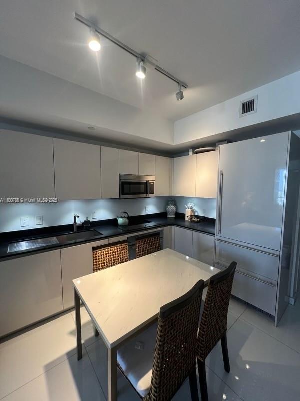 kitchen with sink, gray cabinetry, oven, built in refrigerator, and light tile patterned floors