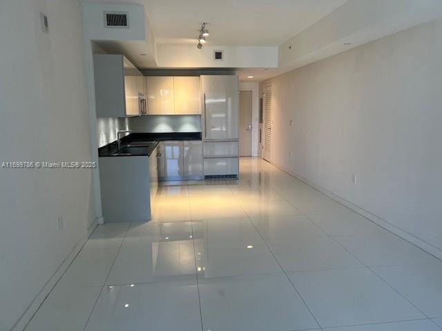 kitchen featuring white refrigerator, sink, and light tile patterned floors