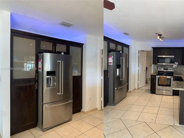 kitchen featuring rail lighting, light tile patterned floors, a textured ceiling, and appliances with stainless steel finishes