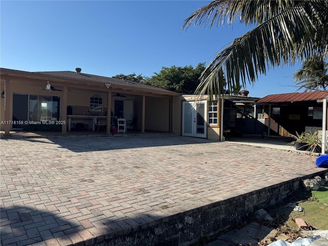 rear view of property with ceiling fan and a patio area