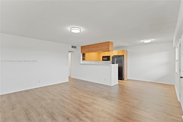 unfurnished living room featuring a textured ceiling and light hardwood / wood-style floors