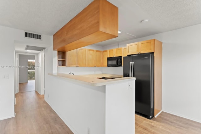 kitchen with light hardwood / wood-style flooring, kitchen peninsula, a textured ceiling, light brown cabinetry, and black appliances