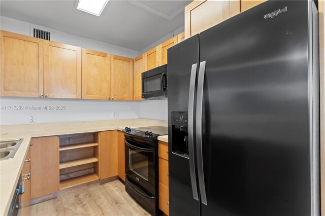 kitchen with sink, light brown cabinetry, light wood-type flooring, and black appliances