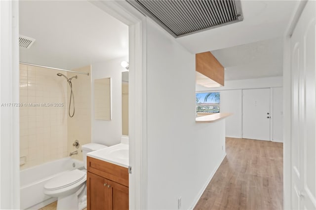 full bathroom with hardwood / wood-style floors, vanity, tiled shower / bath combo, and toilet