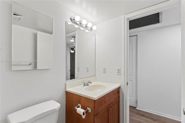 bathroom with wood-type flooring, vanity, and toilet