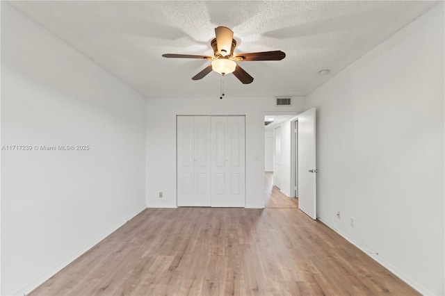 unfurnished bedroom featuring a textured ceiling, light wood-type flooring, a closet, and ceiling fan