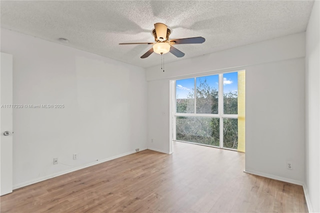 empty room with ceiling fan, light wood-type flooring, and a textured ceiling