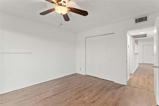 unfurnished bedroom featuring hardwood / wood-style flooring, ceiling fan, a textured ceiling, and a closet