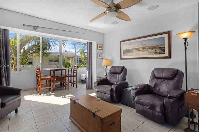 living room featuring ceiling fan, light tile patterned floors, and a textured ceiling