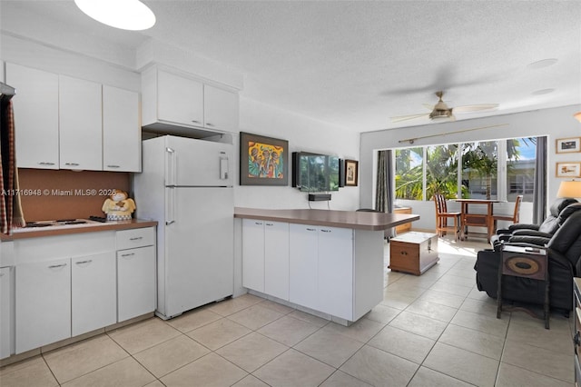 kitchen featuring kitchen peninsula, white refrigerator, white cabinets, and ceiling fan