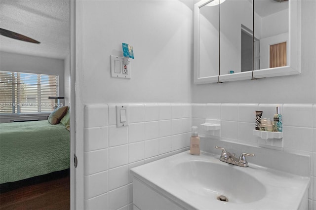 bathroom with tile walls, vanity, and a textured ceiling