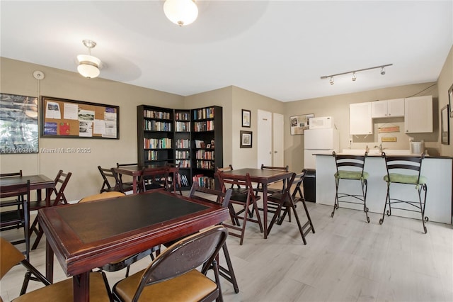 dining space with light wood-type flooring and rail lighting