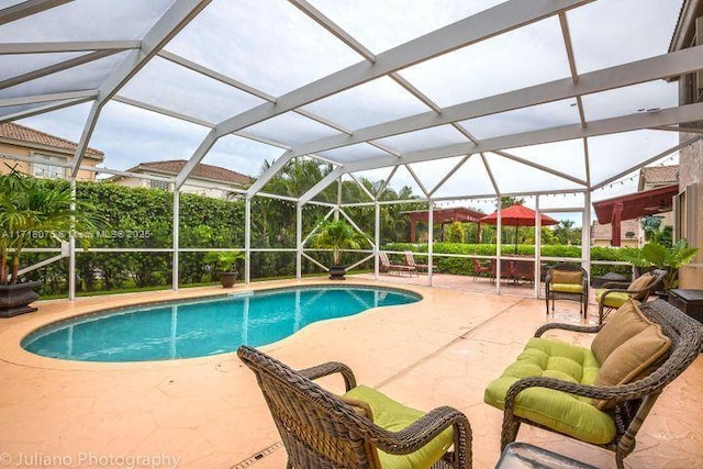 view of swimming pool featuring glass enclosure and a patio