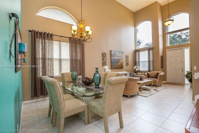 tiled dining room featuring plenty of natural light, a high ceiling, and a chandelier