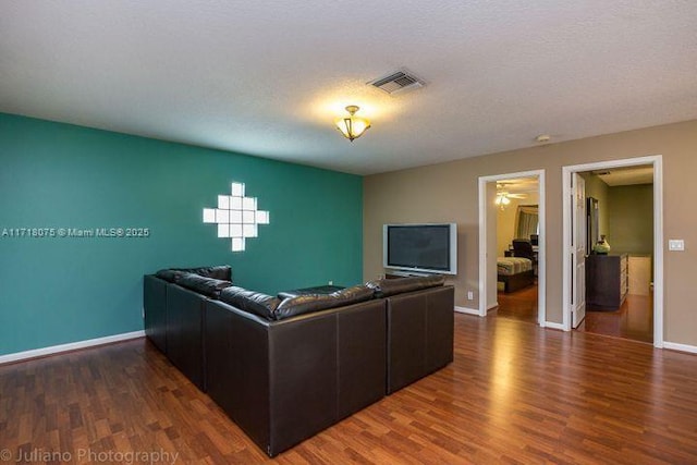 living room with a textured ceiling and dark hardwood / wood-style floors