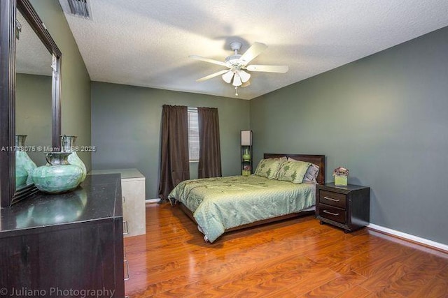 bedroom featuring ceiling fan, wood-type flooring, and a textured ceiling