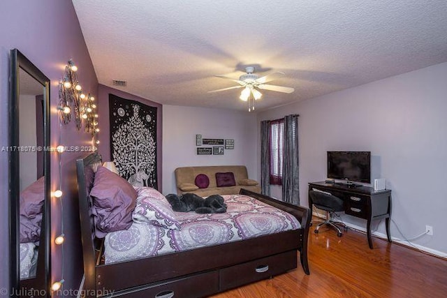 bedroom with ceiling fan, wood-type flooring, and a textured ceiling