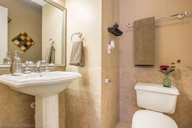 bathroom with toilet and tile walls