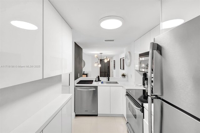 kitchen featuring sink, white cabinets, pendant lighting, and appliances with stainless steel finishes