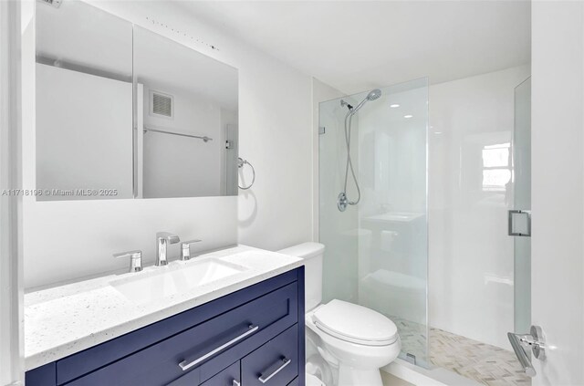 bathroom featuring vanity, toilet, and a shower with door