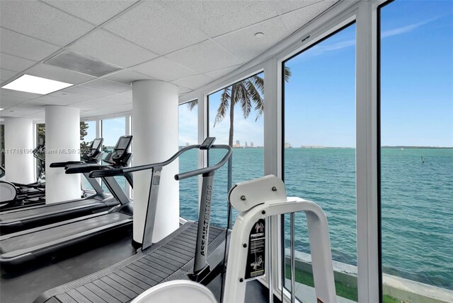 exercise room with a paneled ceiling and a water view