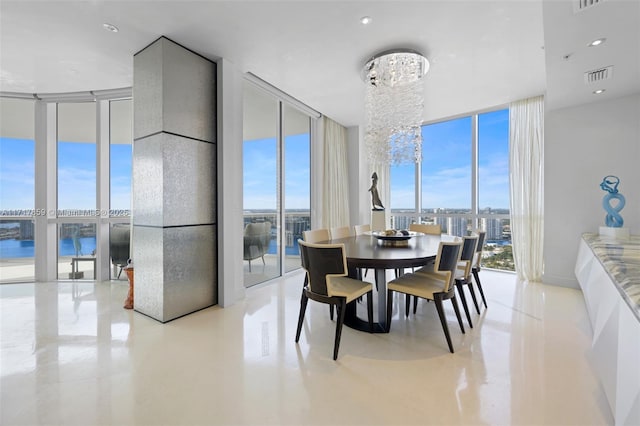 dining area with a water view, a wall of windows, and an inviting chandelier