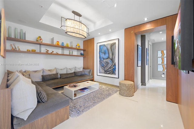 living room featuring a raised ceiling, wooden walls, and a chandelier