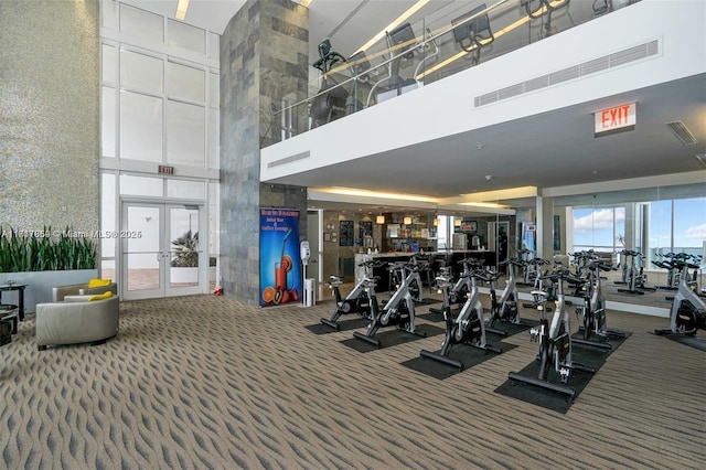 gym featuring bar area, french doors, carpet, and a high ceiling