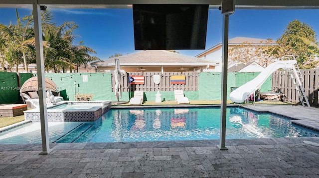 view of swimming pool featuring an in ground hot tub and a water slide