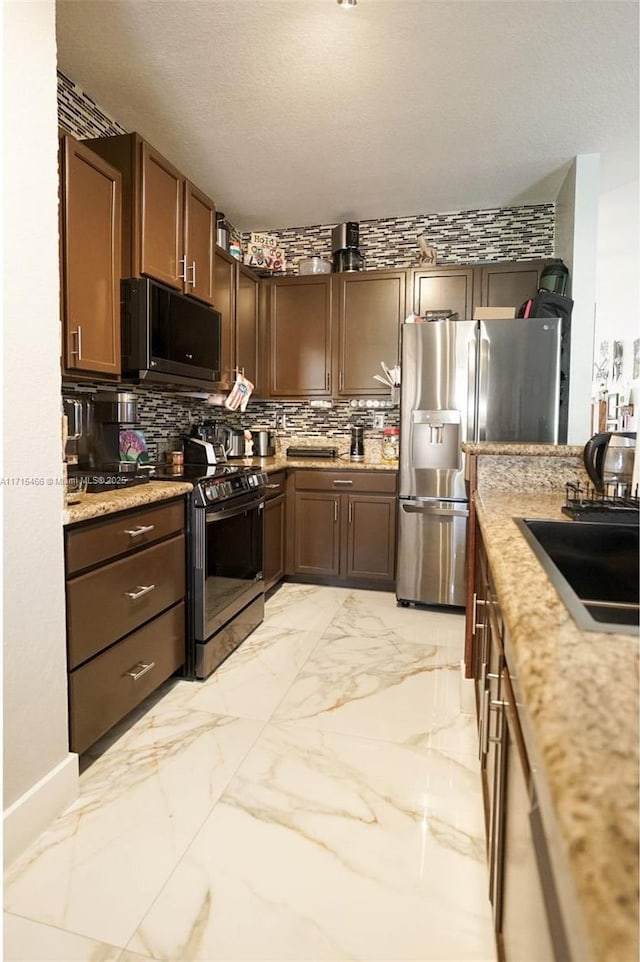 kitchen featuring light stone countertops, stove, tasteful backsplash, and stainless steel fridge with ice dispenser