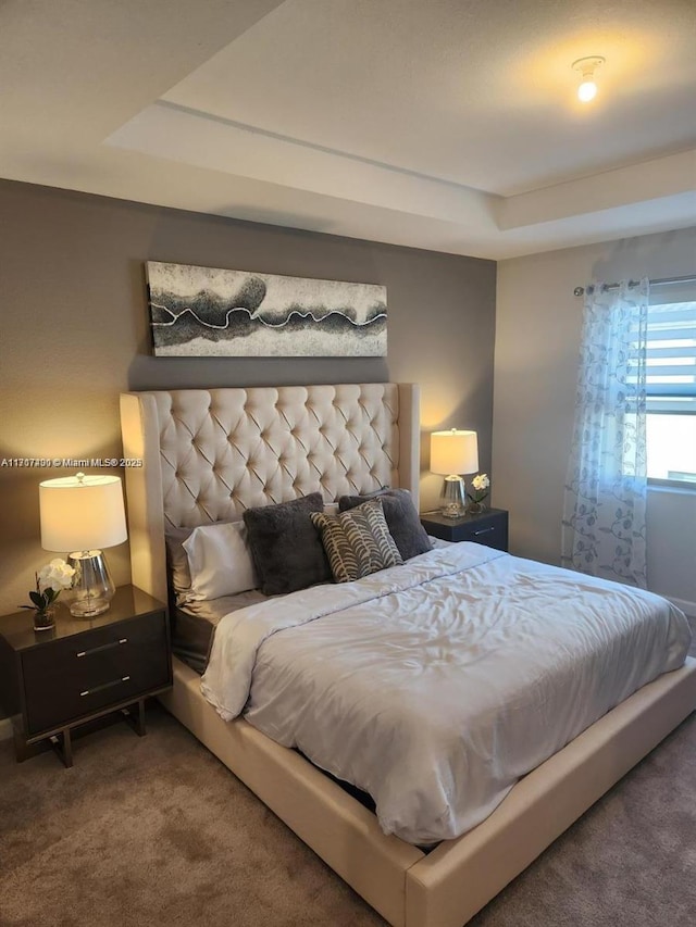 carpeted bedroom with a raised ceiling